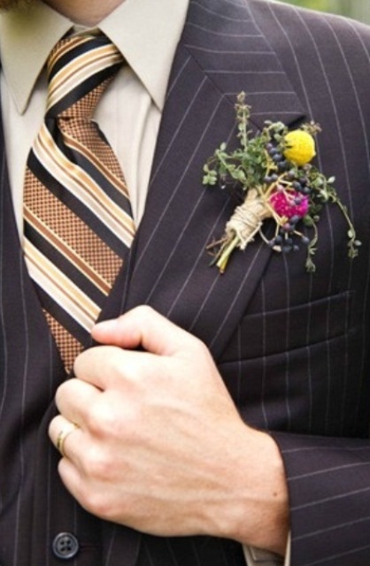 an elegant retro groom's look with a thin striped black three-piece suit, a striped tie and a bright floral boutonniere