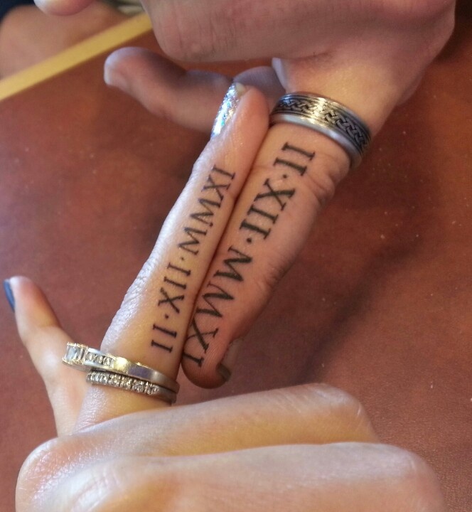 Usual wedding bands paired with wedding date tattoos done with roman numbers on the sides of the fingers