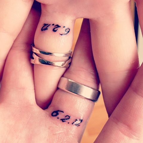 wedding bands and tiny date tattoos made with usual numbers on the back side of the fingers