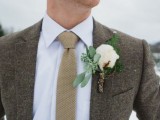 a grey tweed suit, a white button down, a neutral tie and a cotton boutonniere to feel warm on a cold day