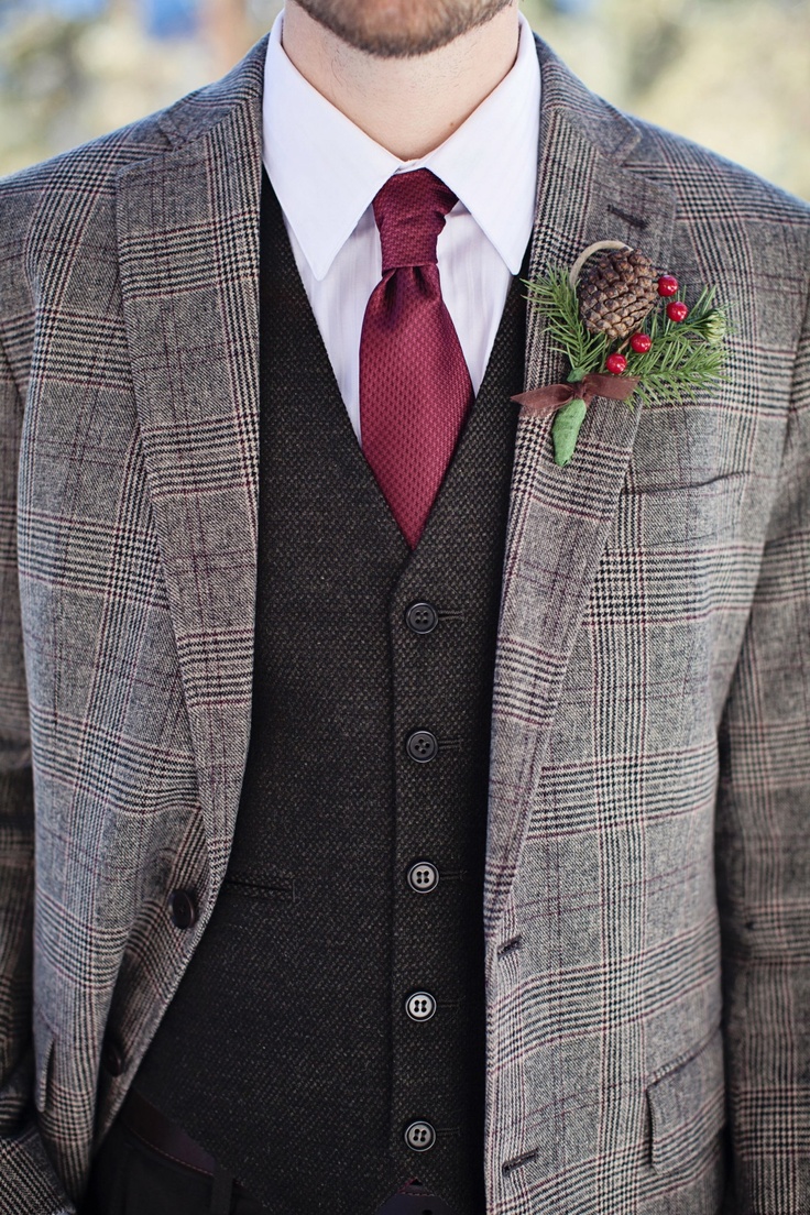 a grey checked tweed suit, a black waistcoat, a burgundy tie, a white button down and a pinecone and berry boutonniere