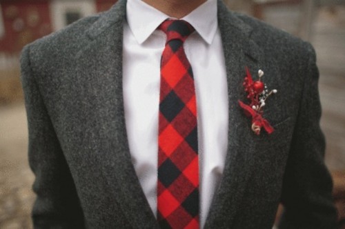 a grey tweed suit, a white button down, a red checked tie and a red boutonniere to add color to the look
