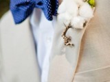 a creamy suit, a white shirt, a navy bow tie with polka dots, a cotton boutonniere