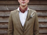 a brown three-piece wedding suit, a white button down, a red neck tie and a boutonniere