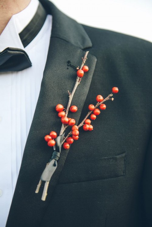 a classic black tux highlighted with a red berry boutonniere is a timeless winter groom's outfit