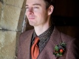 a burgundy tweed three-piece suit, a moody floral shirt, a rust tie and a berry boutonniere