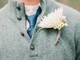 a white button down, a blue tie, a grey sweater over the shirt and a white floral boutonniere for a more casual look