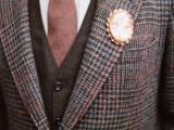 a brown plaid tweed suit, a brown waistcoat, a white button down, a mauve tie and a vintage brooch boutonniere
