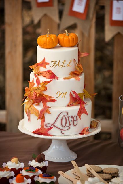 a cute fall wedding or bridal shower cake with calligraphy and bright fall leaves plus small pumpkins on top