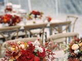 a chic and bold fall bridal shower centerpiece of deep red blooms, foliage and some berries