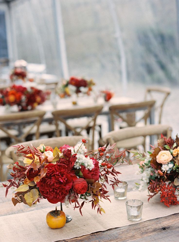 A chic and bold fall bridal shower centerpiece of deep red blooms, foliage and some berries