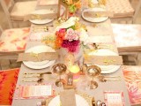 a bright and glam fall bridal shower tablescape done with bold floral arrangements, gold touches, colorful menus and burlap napkins