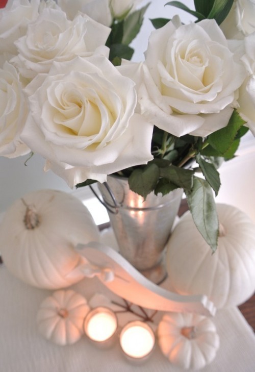 a chic centerpiece of white roses, white pumpkins and candles can be easily DIYed