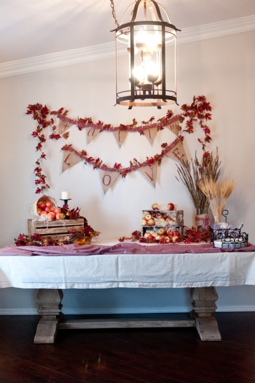 a fall bridal shower station decorated with bright leaves, apples and dried herbs in crates and baskets for a rustic feel