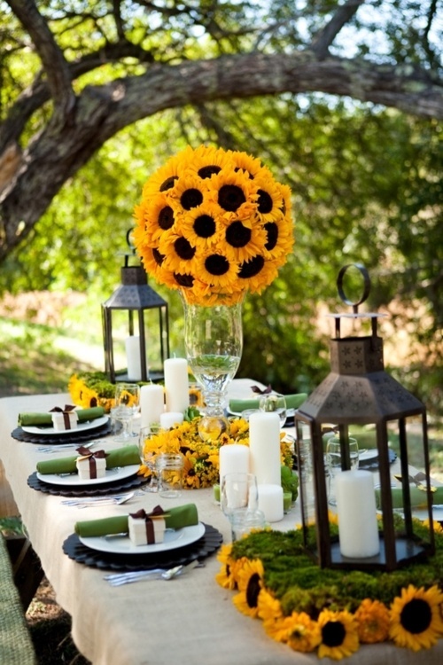 a fall bridal shower tablescape with candles, candle lanterns, bright sunflower decor