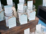jars on wooden boxes with escort cards and tags with yarn bows are cool for any wedding