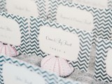 a tray with beach sand, pink sea urchins with chevron escort cards is a chic and elegant way to display escort cards