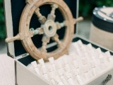 a box with beach sand, escort cards in test tubes and a steering wheel for a nautical wedding