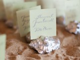 a tray with beach sand, silver seashells and escort cards attached to the them is a cool idea for a beach wedding