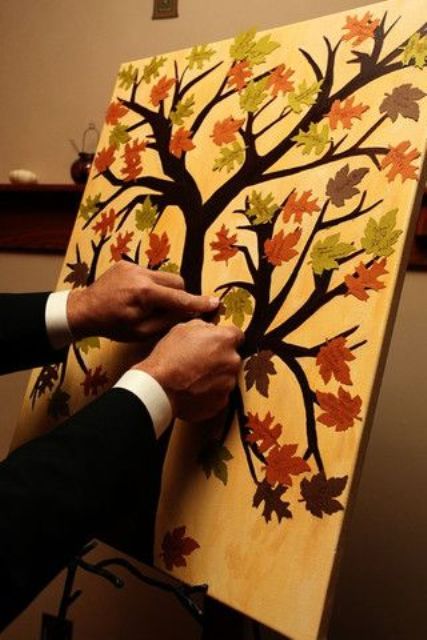 a painted tree and colorful leaves attached to it is a cute and casual idea for a fall wedding