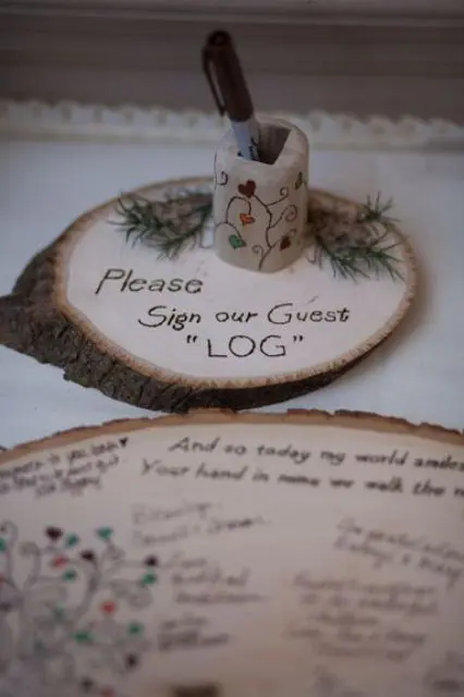 a wood slice with calligraphy and some fir branches is a stylish rustic idea for a fall wedding