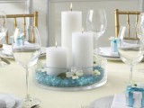 a glass bowl with blue crystals and pillar candles is a simple and very budget-friendly idea