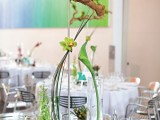 greenery, driftwood, green orchids on a stand for a chic and bright wedding centerpiece