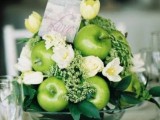 a green apple topiary with greenery, white blooms and a card on top for a bright wedding