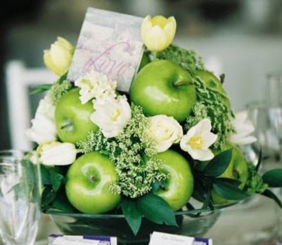 A green apple topiary with greenery, white blooms and a card on top for a bright wedding