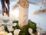 moss, petals and a tree branch cut with a wood burnt number is a nice idea for a fall rustic or woodland wedding