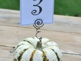 a pumpkin with a table number on a wire piece is a stylish rustic decoration for the fall