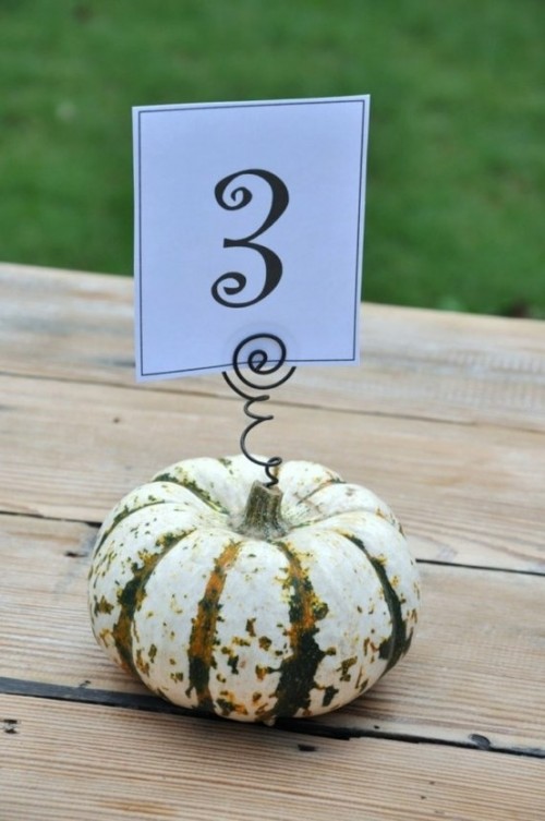 a pumpkin with a table number on a wire piece is a stylish rustic decoration for the fall
