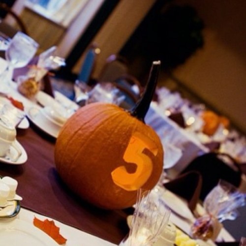 a jack-o-lantern with a carved table number and a candle inside is perfect for both fall and Halloween weddings