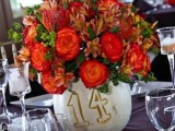 a white pumpkin with a painted table number and bright blooms and leaves is a stylish fall centerpiece