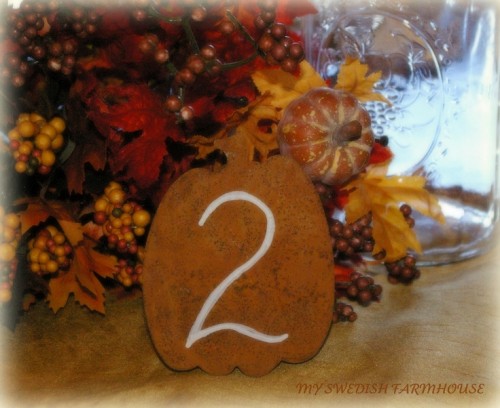an orange plywood pumpkin with a table number is a nice decoration for a fall tablescape