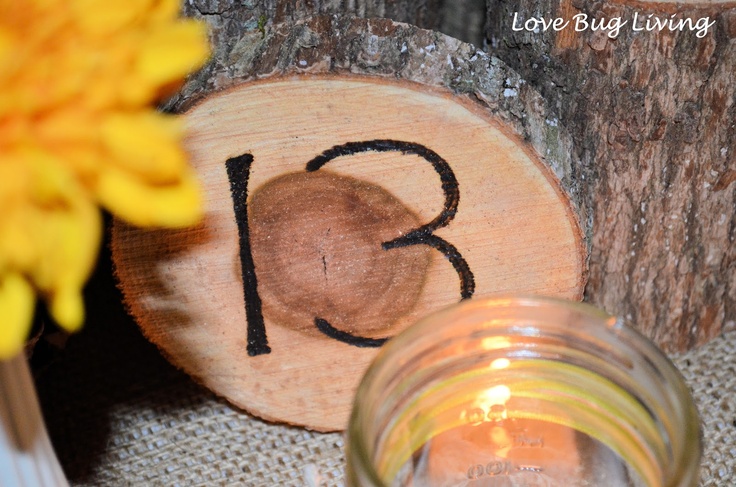 A burnt wood slice with a table number and a candle is a very stylish idea for a rustic fall wedding table setting