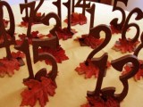 stained wooden table numbers with bright leaves are very bold and will fit a rustic fall tablescape