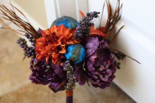 a creative Halloween wedding bouquet of purple and orange blooms, berries, dried grasses and blue spheres