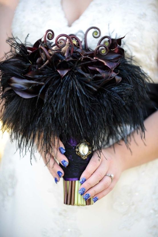 a dark romantic wedding bouquet of deep purple callas, lotus, dark foliage and black feathers for Halloween