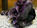 a dark Halloween wedding bouquet of deep purple callas, black and purple feathers, black tulle