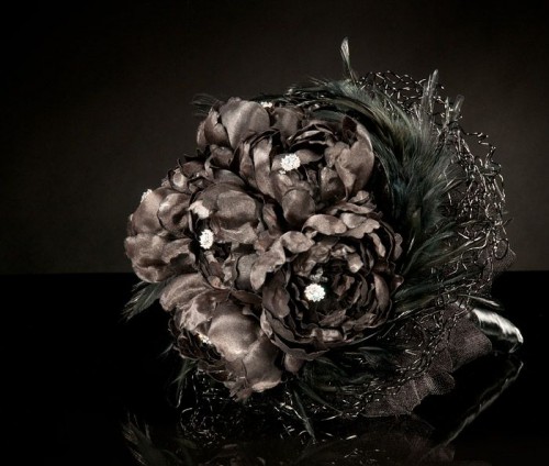a black Halloween wedding bouquet of blooms, feathers, embellishments and with a dark tulle wrap
