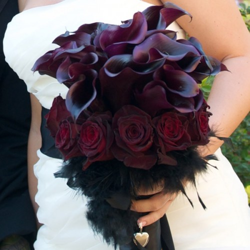 a decadent Halloween bouquet of deep purple callas, burgundy roses, black feathers is a stylish piece