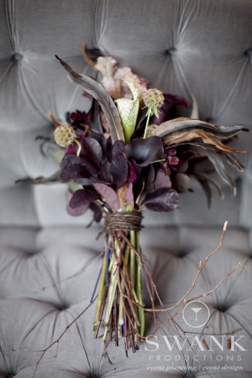 a dark Halloween bouquet with deep purple callas, pastel blooms and feathers and dark foliage is wow