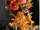 an orange and red wedding bouquet with thistles and cascading blooms is a stylish idea for Halloween