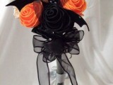 a fabric Halloween wedding bouquet of orange, black and white blooms and fabric bats plus a tulle bow
