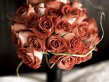 a rust-colored rose wedding bouquet with twigs is a stylish and bold idea for a moody Halloween wedding