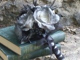 a mourning wedding bouquet of white blooms, berries, feathers and with a black ribbon wrap