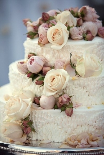 a textural white wedding cake with ivory and mauve blooms for decor is a very chic idea