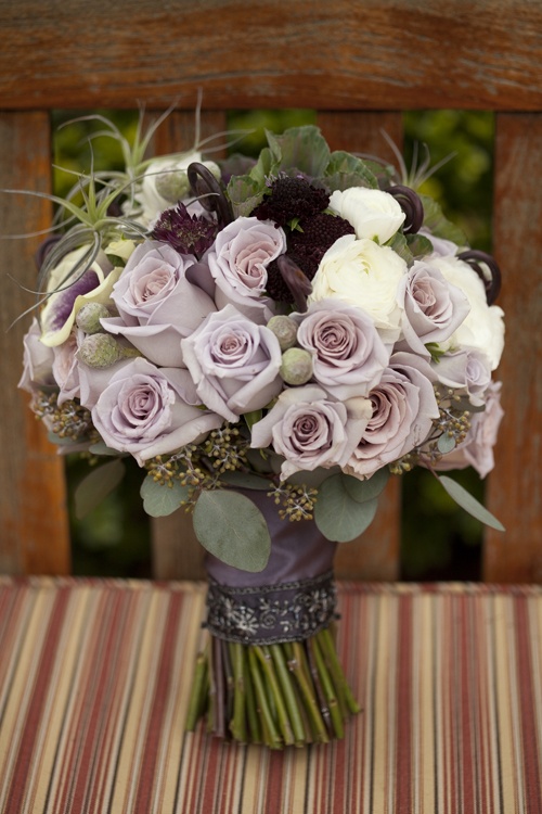a wedding bouquet with mauve, dark, white, deep purple blooms, greenery and air plants