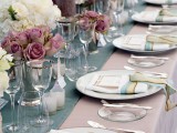 an elegant blue, mauve and blush wedding tablescape with mauve candles and roses that make it unusual